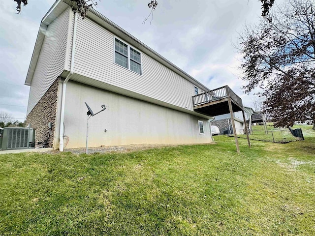 rear view of house with a balcony, a yard, and central AC