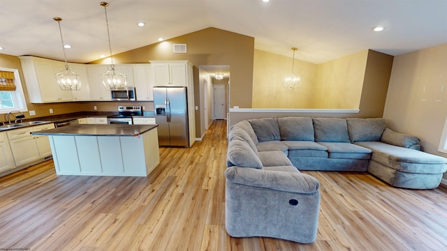 kitchen with decorative light fixtures, light hardwood / wood-style flooring, stainless steel appliances, and vaulted ceiling