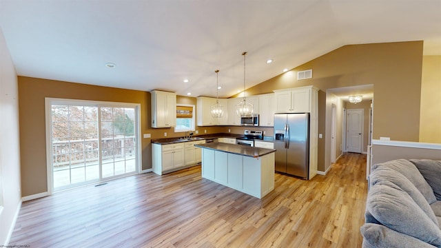 kitchen featuring lofted ceiling, sink, light hardwood / wood-style flooring, appliances with stainless steel finishes, and decorative light fixtures