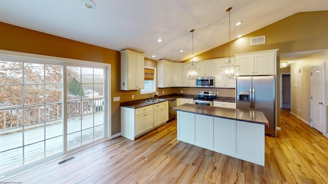 kitchen featuring appliances with stainless steel finishes, light wood-type flooring, vaulted ceiling, and pendant lighting