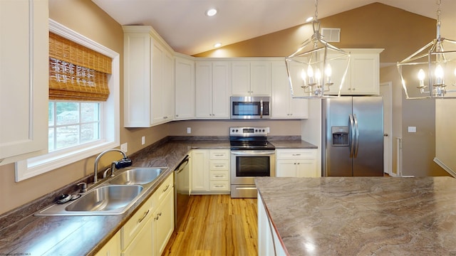 kitchen with hanging light fixtures, stainless steel appliances, and lofted ceiling