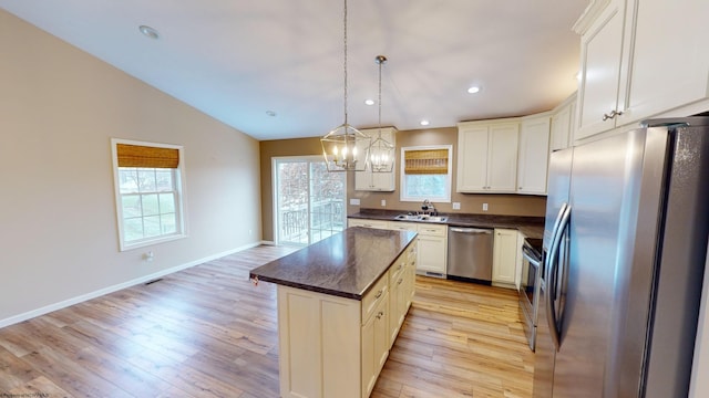 kitchen featuring appliances with stainless steel finishes, light wood-type flooring, a kitchen island, and plenty of natural light