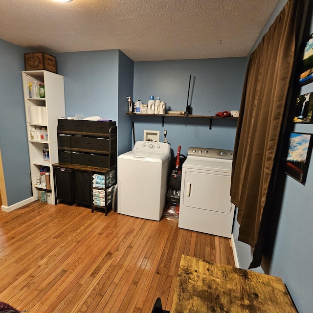 laundry room with washer and dryer, light wood-type flooring, and a textured ceiling