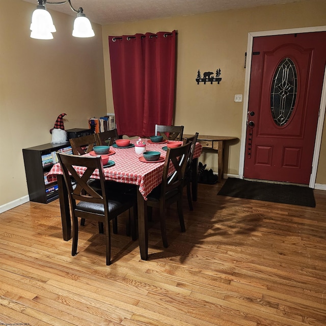 dining area with light wood-type flooring and an inviting chandelier