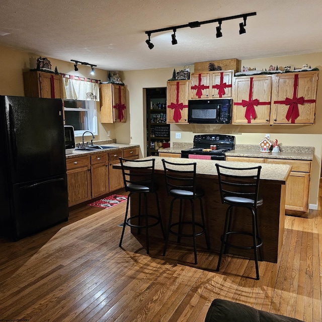 kitchen with black appliances, wood-type flooring, and sink