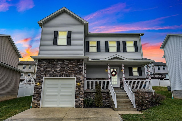 view of front of home featuring a yard, covered porch, and a garage