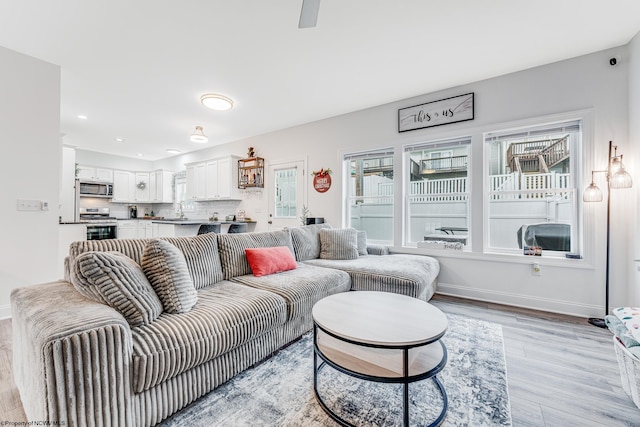 living room featuring plenty of natural light, light hardwood / wood-style floors, and sink