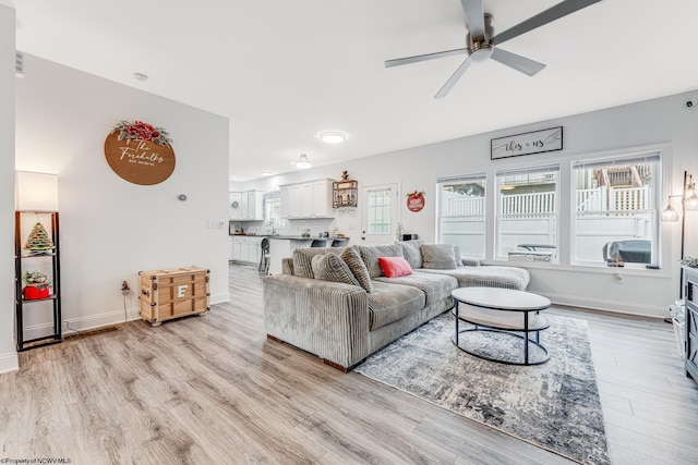 living room with ceiling fan, plenty of natural light, and light hardwood / wood-style floors