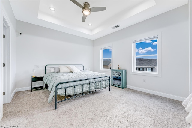 bedroom featuring carpet, a raised ceiling, and ceiling fan