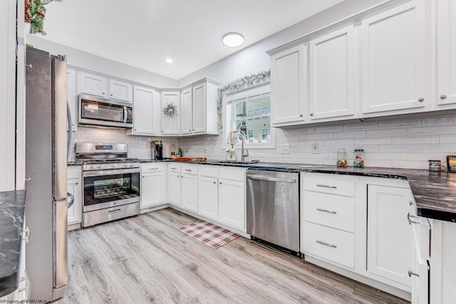 kitchen with sink, stainless steel appliances, backsplash, light hardwood / wood-style floors, and white cabinets