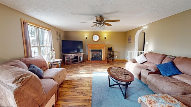 living room with light wood-type flooring, a textured ceiling, and ceiling fan