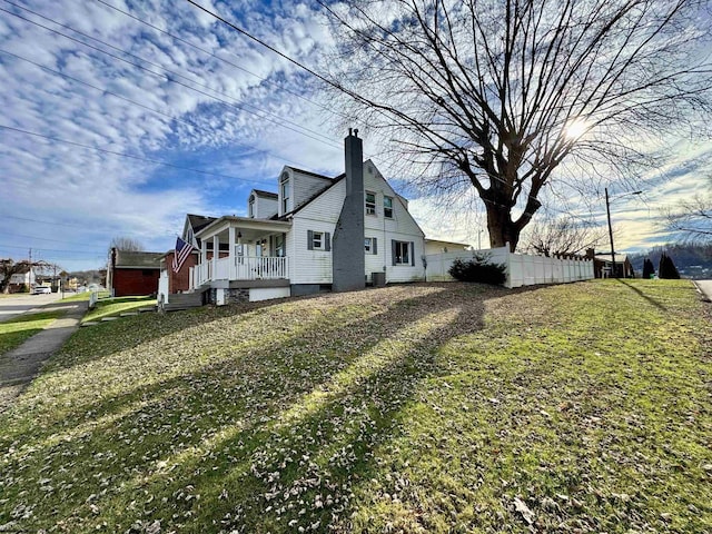 view of side of property with a lawn and covered porch