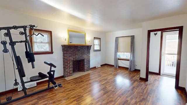 exercise room with wood-type flooring, a brick fireplace, and a wealth of natural light