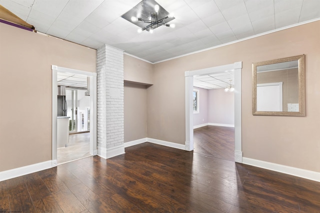 unfurnished room featuring dark hardwood / wood-style floors, ornamental molding, and a chandelier