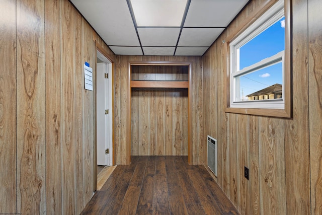 hallway featuring a paneled ceiling, dark hardwood / wood-style floors, and wooden walls