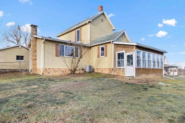 rear view of house with a sunroom, a yard, and central AC