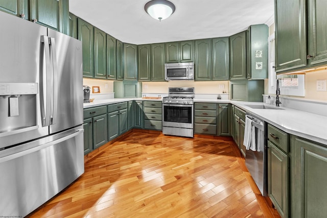 kitchen with green cabinets, sink, light hardwood / wood-style flooring, and appliances with stainless steel finishes