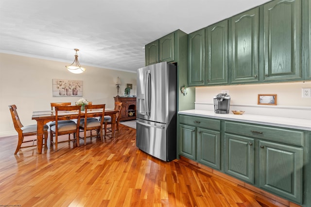 kitchen featuring pendant lighting, crown molding, light hardwood / wood-style flooring, green cabinetry, and stainless steel fridge