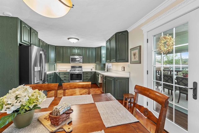 kitchen featuring sink, ornamental molding, green cabinetry, and appliances with stainless steel finishes