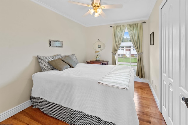 bedroom with ceiling fan, wood-type flooring, crown molding, and a closet