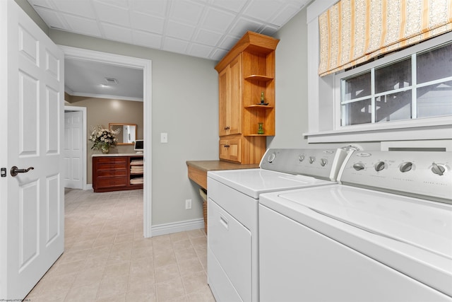 laundry area featuring washing machine and clothes dryer, crown molding, light tile patterned flooring, and cabinets