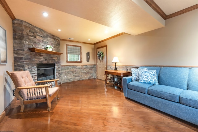 living room featuring hardwood / wood-style floors, a stone fireplace, and crown molding