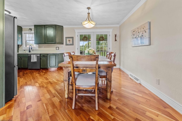 dining room with sink, french doors, crown molding, and light hardwood / wood-style flooring