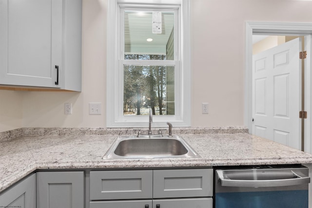 kitchen with gray cabinets, dishwasher, sink, and light stone countertops