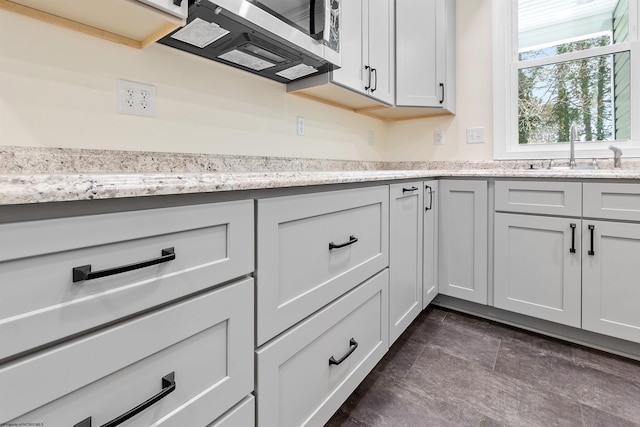 kitchen with white cabinets, light stone countertops, and sink