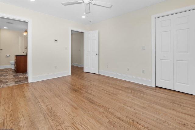 unfurnished bedroom with connected bathroom, ceiling fan, a closet, and light wood-type flooring