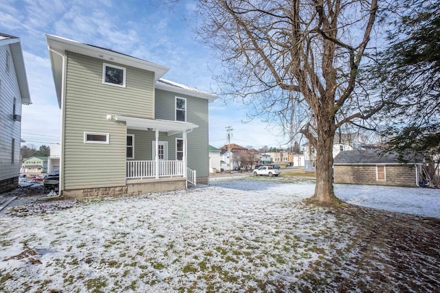 snow covered rear of property with covered porch