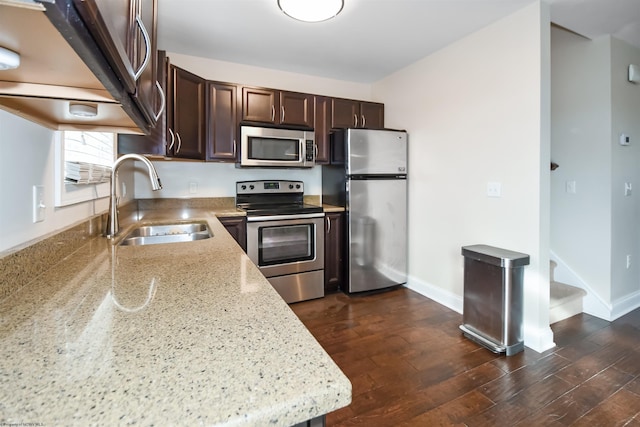 kitchen featuring light stone countertops, appliances with stainless steel finishes, dark brown cabinetry, sink, and dark hardwood / wood-style floors