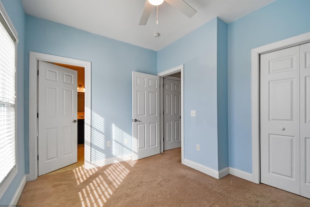 unfurnished bedroom with ceiling fan, light carpet, and a closet