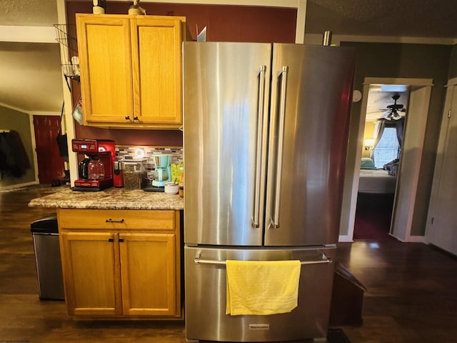 kitchen with stainless steel refrigerator, light stone counters, ceiling fan, and dark wood-type flooring