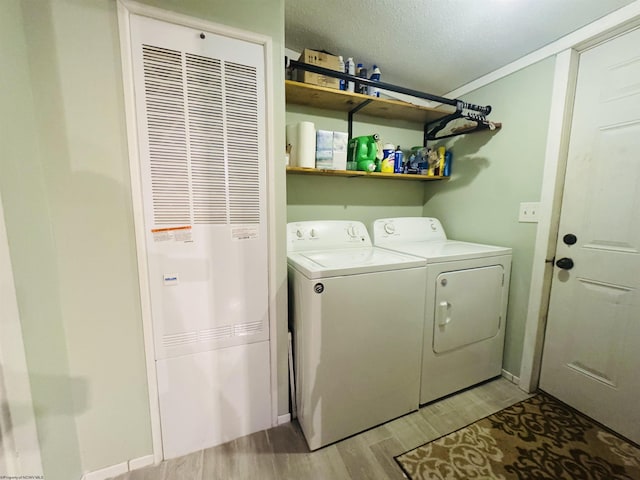 laundry area with washer and clothes dryer, light wood-type flooring, and a textured ceiling