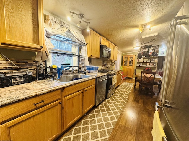 kitchen with sink, stainless steel appliances, light stone counters, dark hardwood / wood-style flooring, and a textured ceiling