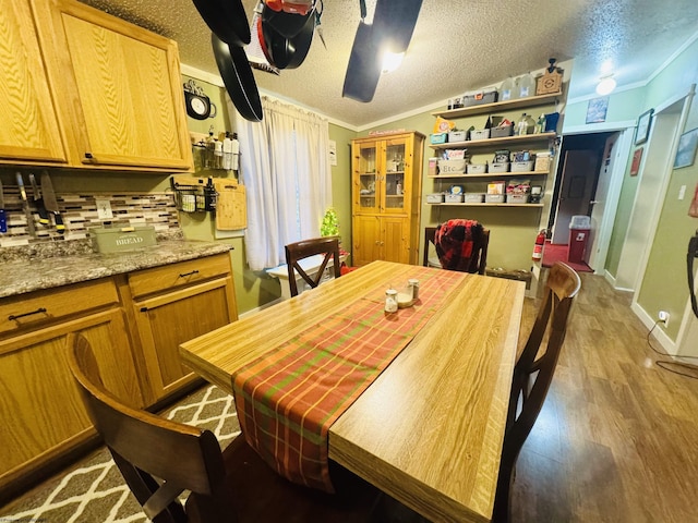 dining space featuring hardwood / wood-style floors, a textured ceiling, and crown molding