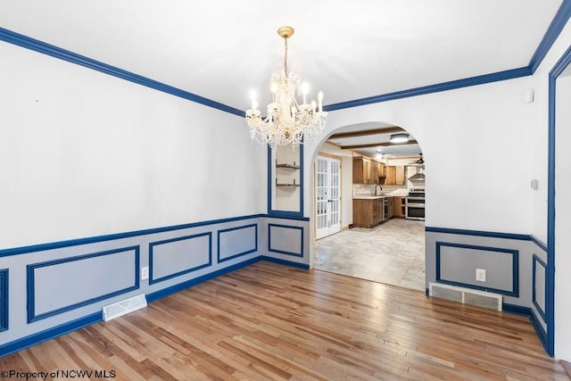 unfurnished dining area featuring sink, ornamental molding, light hardwood / wood-style flooring, and an inviting chandelier