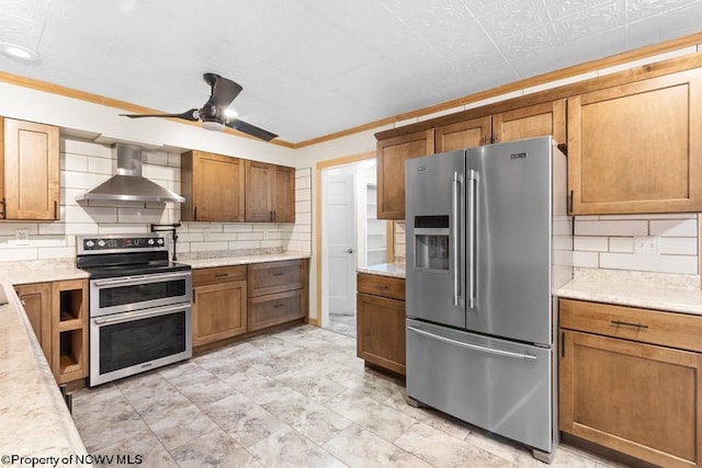 kitchen featuring ceiling fan, wall chimney exhaust hood, tasteful backsplash, appliances with stainless steel finishes, and ornamental molding