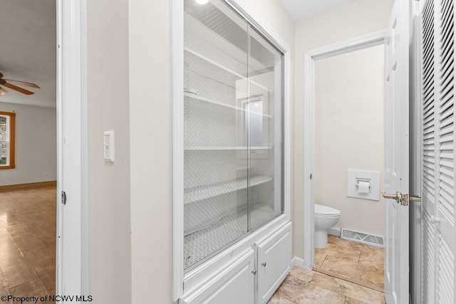 bathroom with ceiling fan and toilet