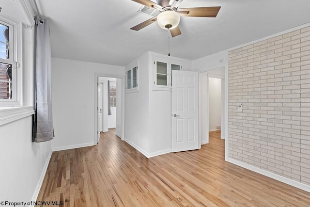 empty room featuring ceiling fan, light hardwood / wood-style flooring, and brick wall