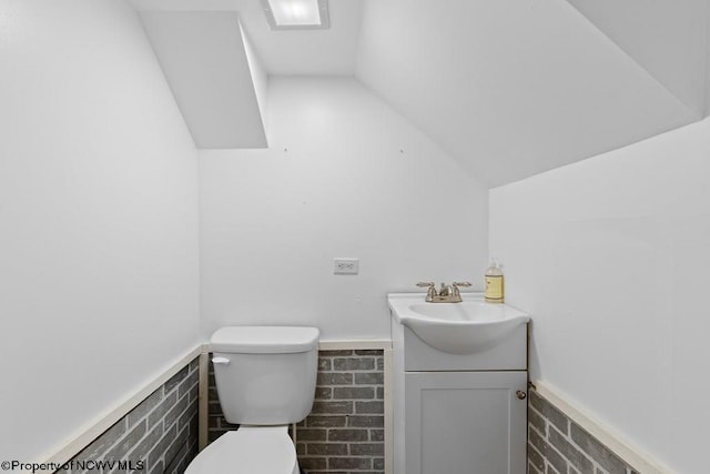 bathroom with vanity, toilet, and lofted ceiling