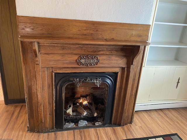 details featuring a baseboard radiator, a wood stove, and hardwood / wood-style flooring