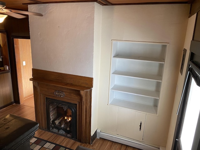 interior space featuring baseboard heating, ceiling fan, and hardwood / wood-style flooring