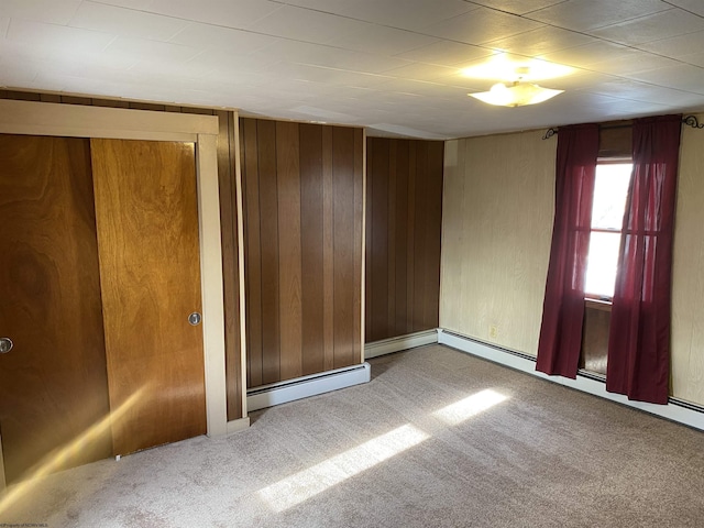 unfurnished room featuring carpet flooring and wooden walls