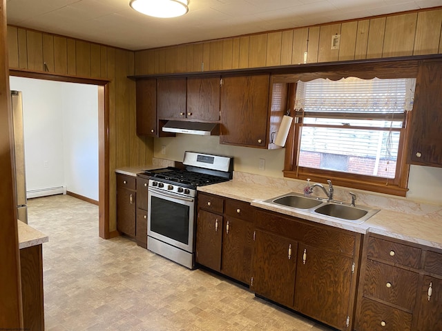 kitchen featuring dark brown cabinetry, stainless steel appliances, wood walls, and sink