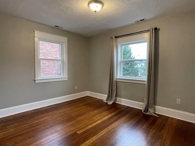 empty room featuring a textured ceiling and dark wood-type flooring