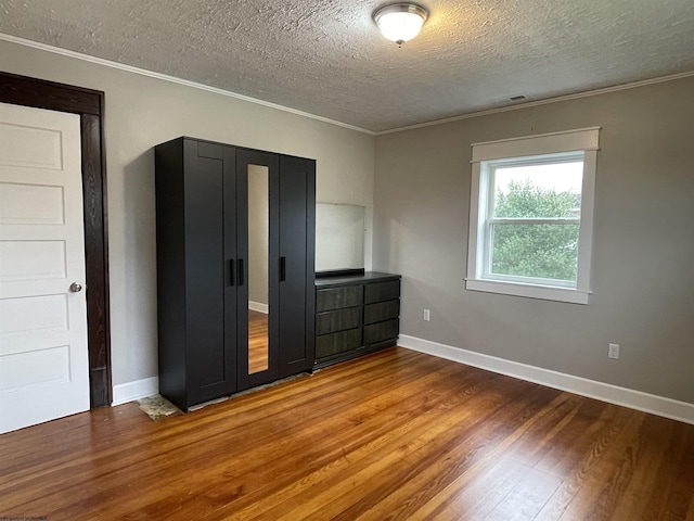 unfurnished bedroom featuring hardwood / wood-style floors, a textured ceiling, and crown molding