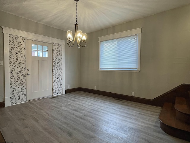 entrance foyer with hardwood / wood-style floors and a notable chandelier