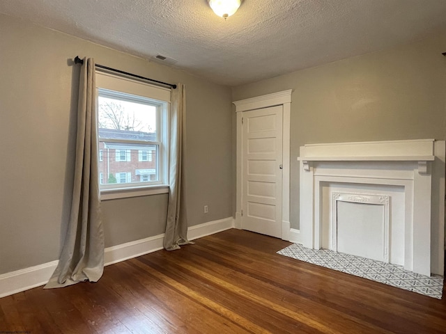 unfurnished living room with dark hardwood / wood-style flooring and a textured ceiling